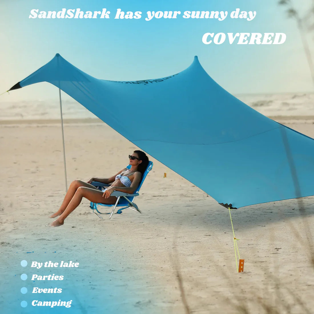 Woman sitting under a large blue sandshade on a beach with text overlay.