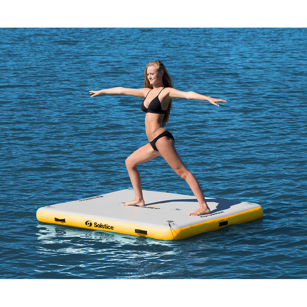 Solstice inflatable dock platform for lakes with woman doing yoga, floating water mat for sandbar, swimming, and paddleboarding, durable drop-stitch construction